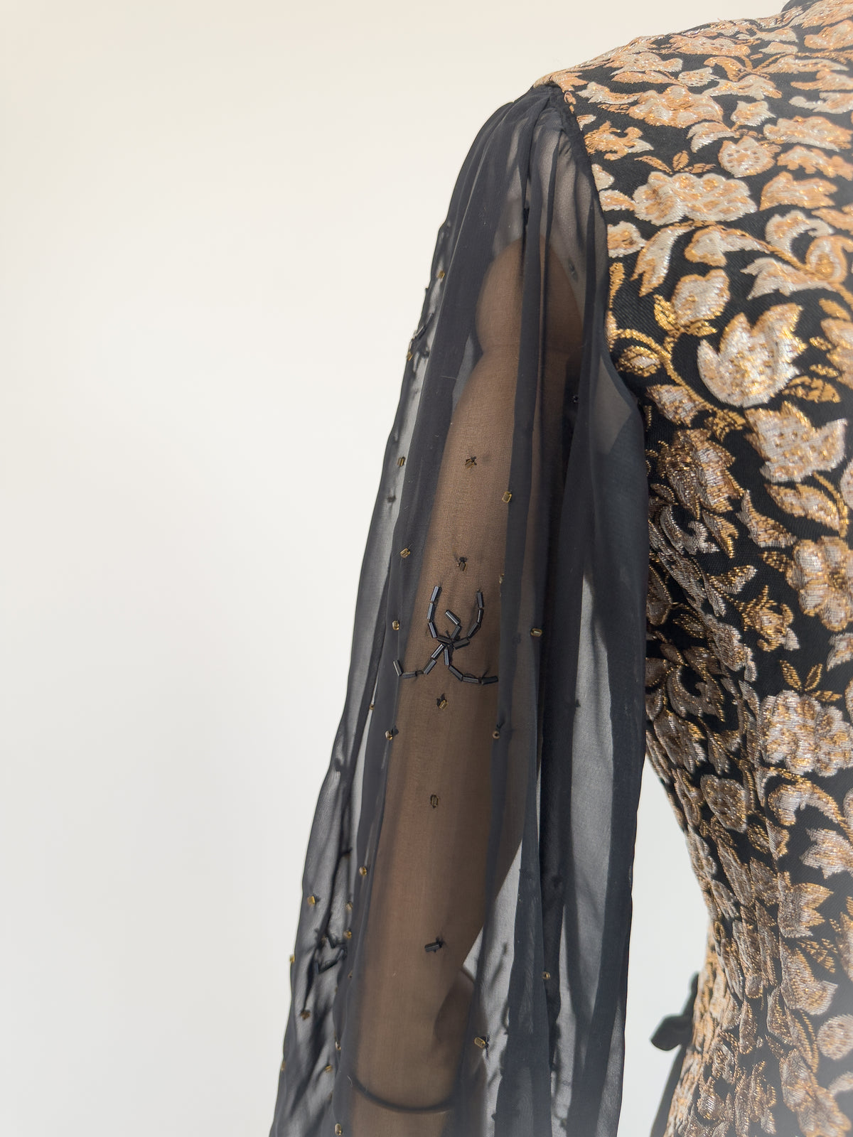 close-up of the sheer black chiffon sleeve on the gold brocade blouse, hand-beaded with a spider motif and scattered gold beads