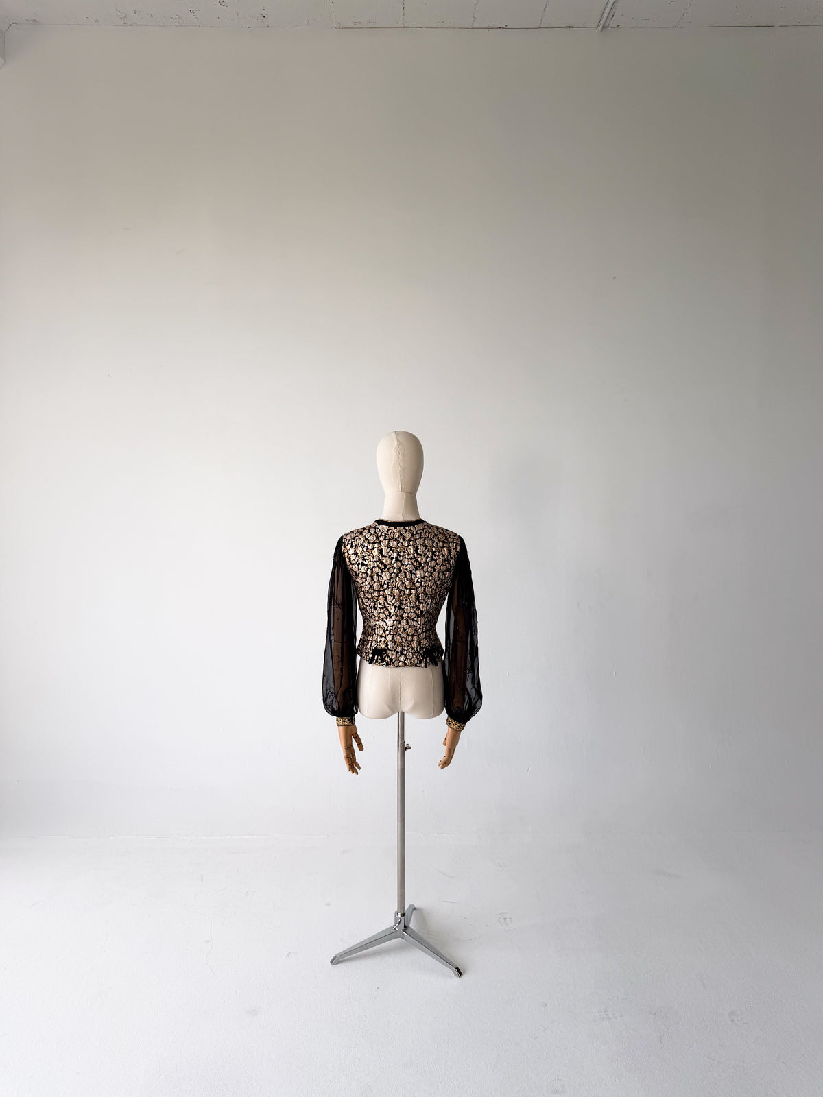 back view of the gold brocade blouse with sheer black chiffon sleeves, on a dress form on a tripod stand