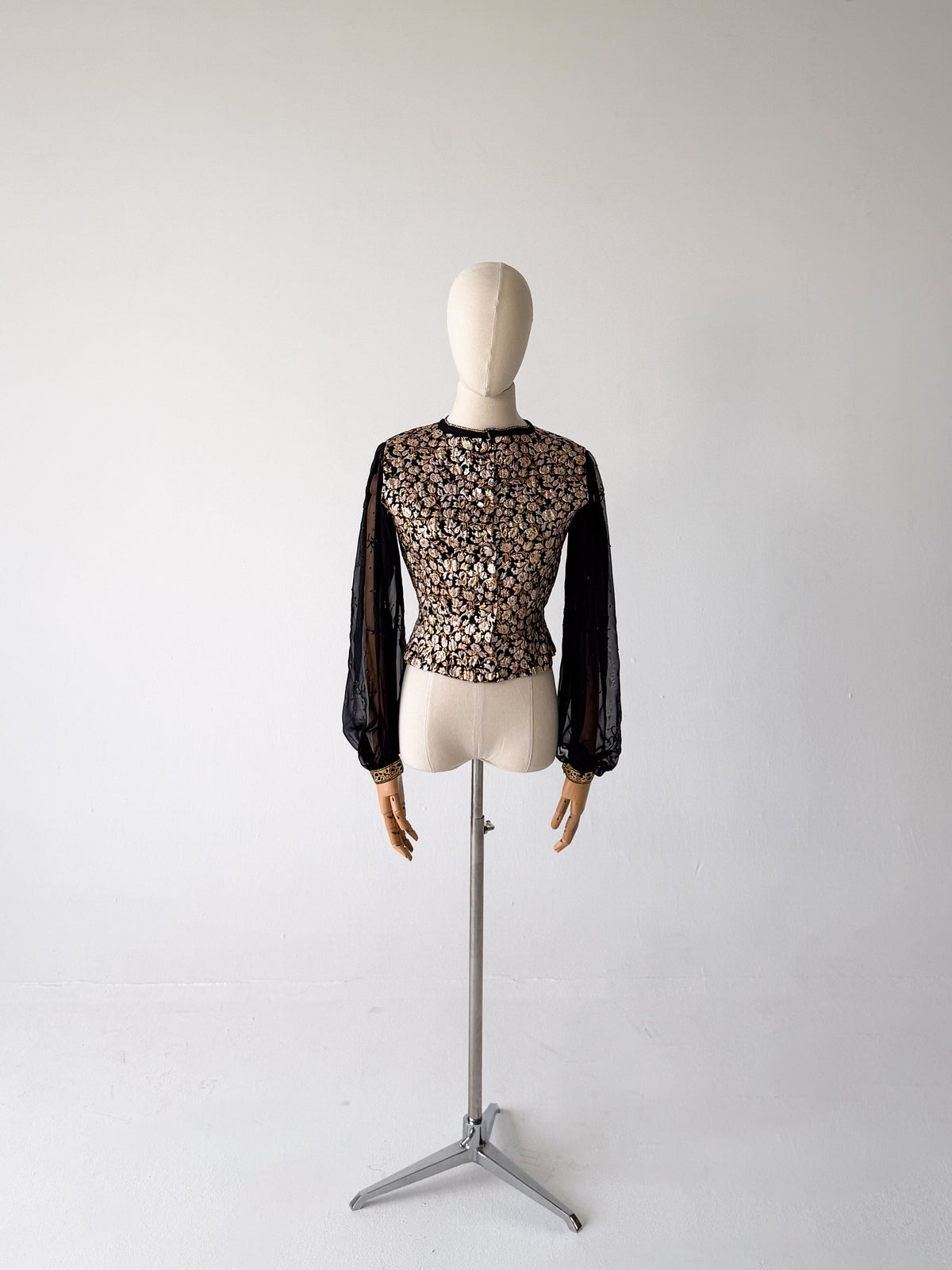 full-length front view of the gold brocade blouse with sheer black chiffon sleeves, on a dress form on a tripod stand