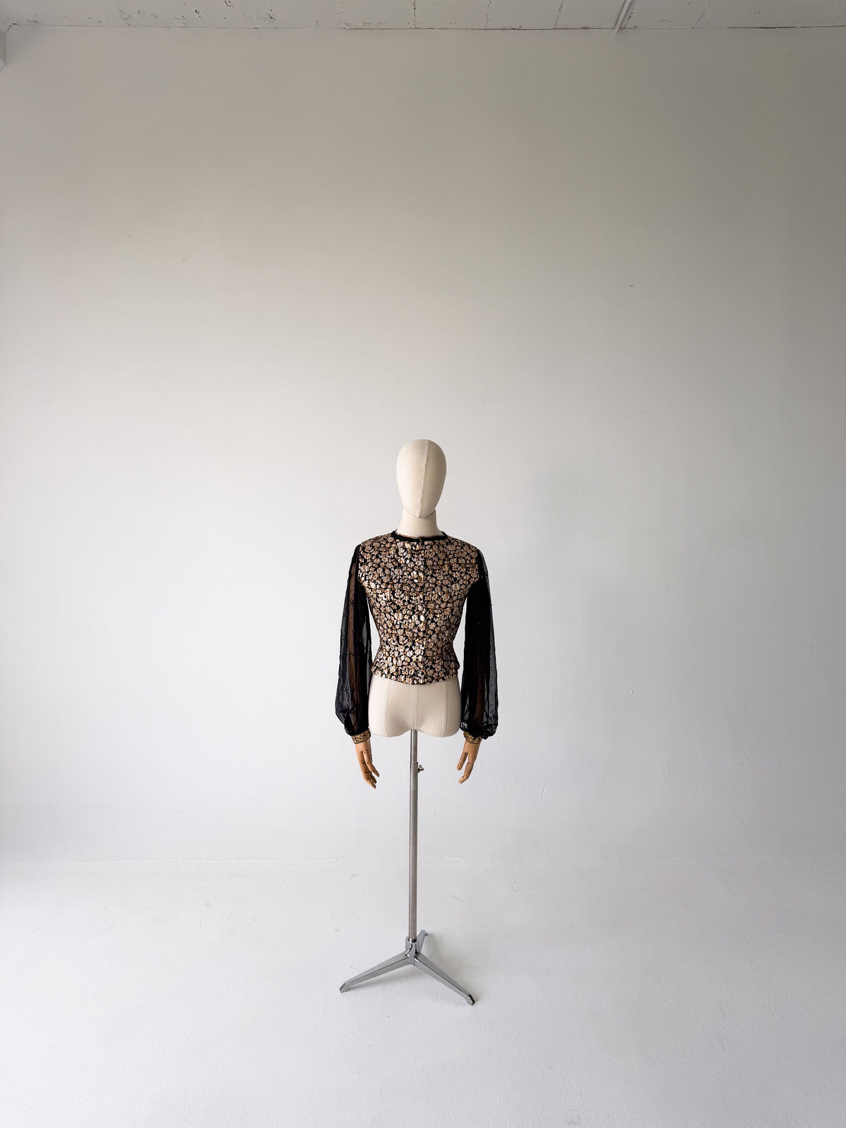 full-length front view of the gold brocade blouse with sheer black chiffon sleeves, on a dress form on a tripod stand