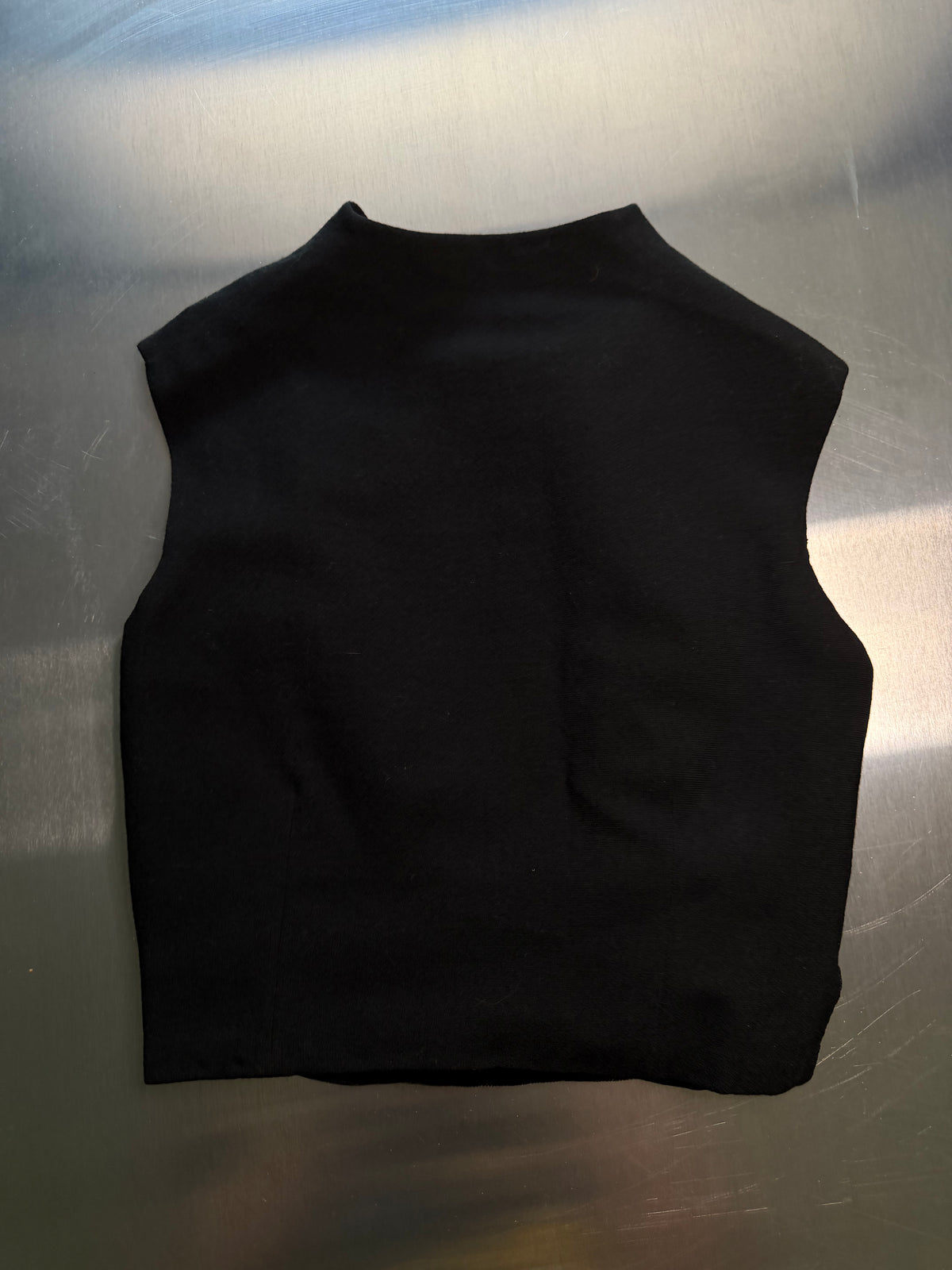 black scalloped vest laid flat, back view