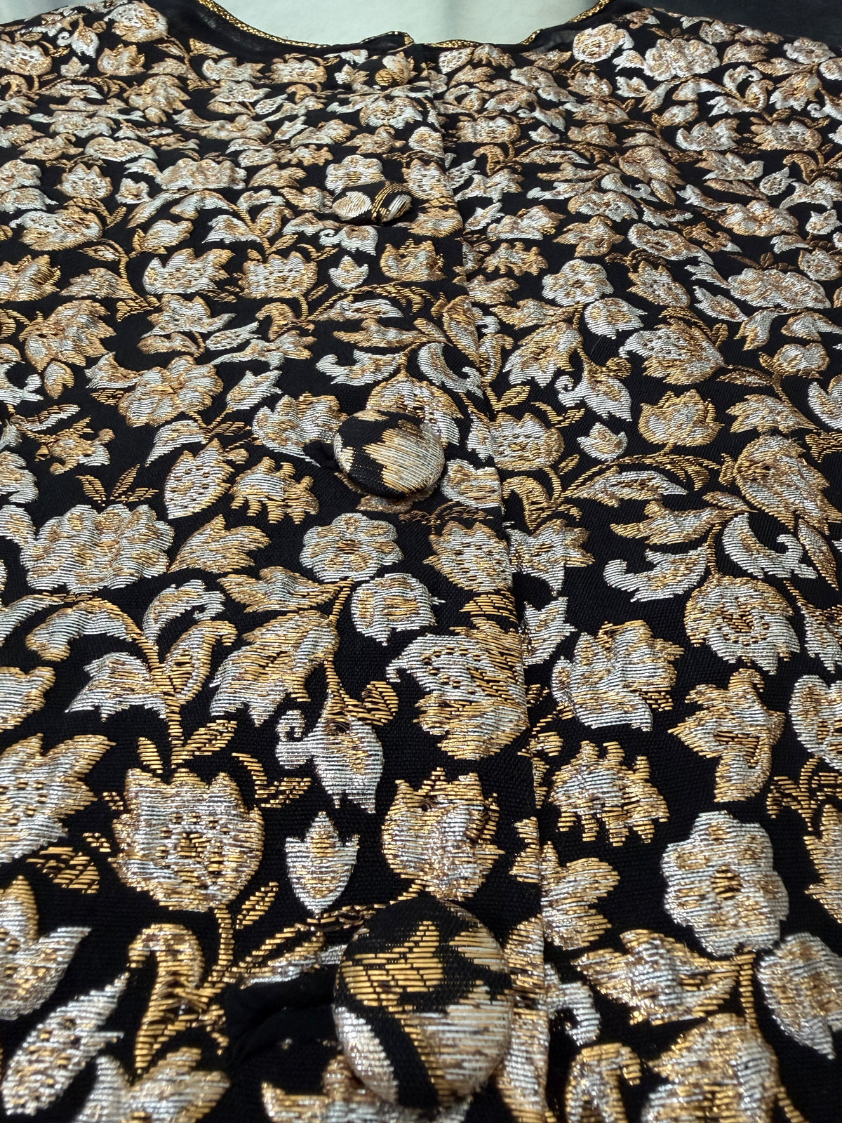 close-up of the gold and silver floral brocade fabric on the blouse, showing two covered buttons