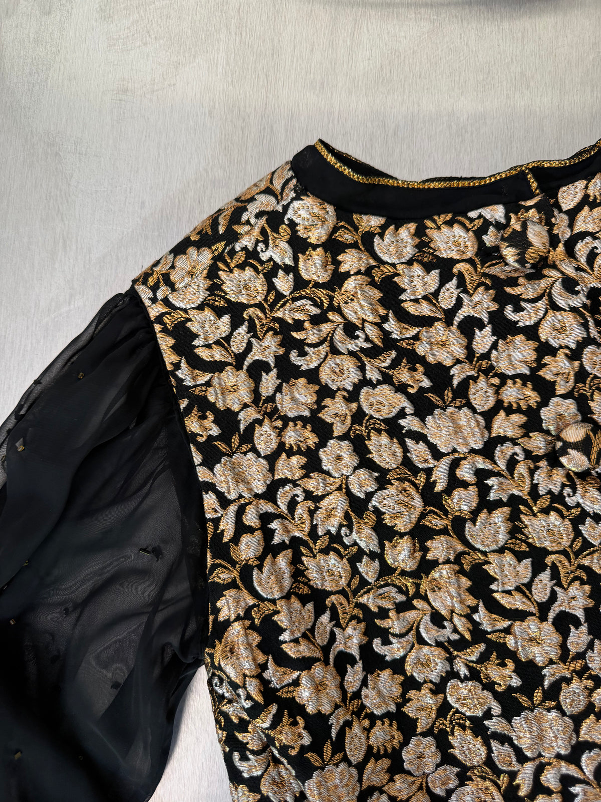 close-up of the gold brocade blouse's collar and shoulder seam, showing the gold chain trim along the collar edge