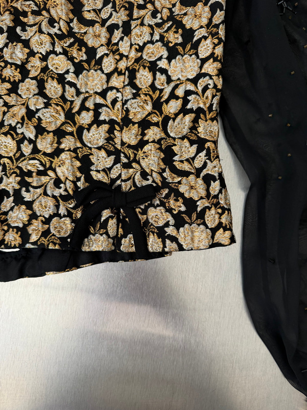 close-up of a small black velvet bow at the back seam of the gold brocade blouse