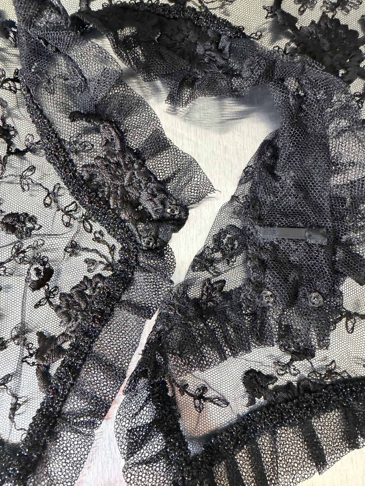 close-up of the black lace shawl's collar, showing the ruffled trim and metal hook-and-eye closure at the neck