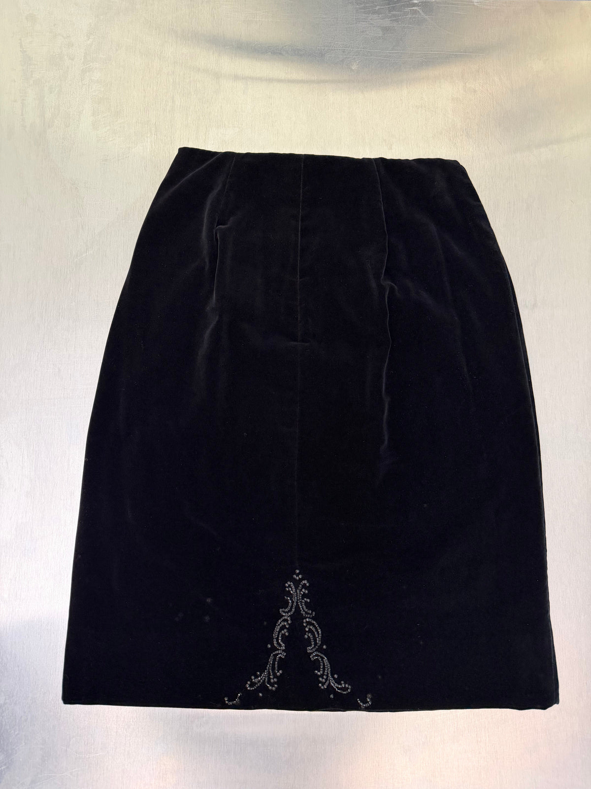 black velvet pencil skirt laid flat, showing the beaded filigree motif at the hem