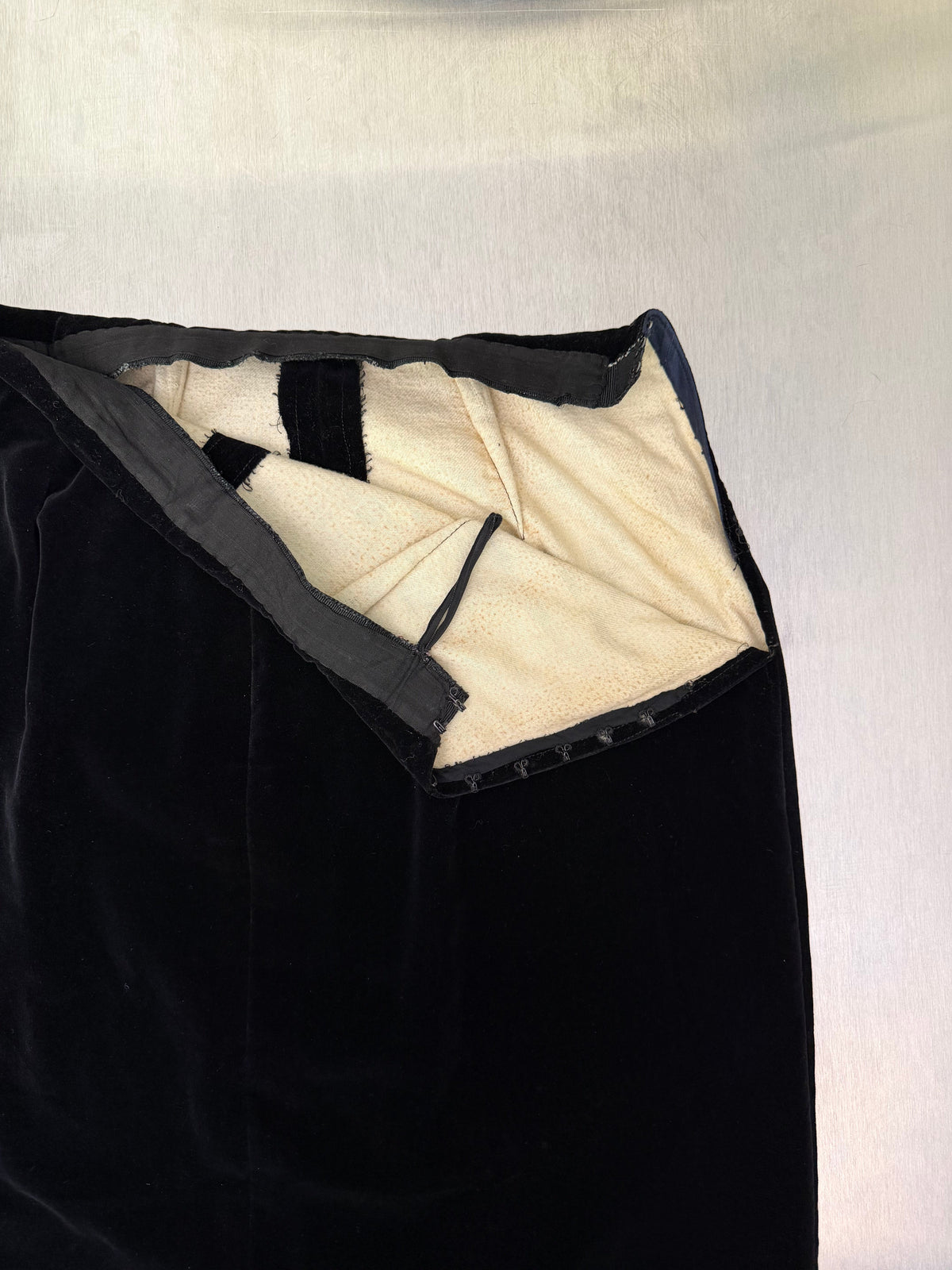 interior view of the black velvet skirt's waistband, folded open to show the hook-and-eye closure and taped hem