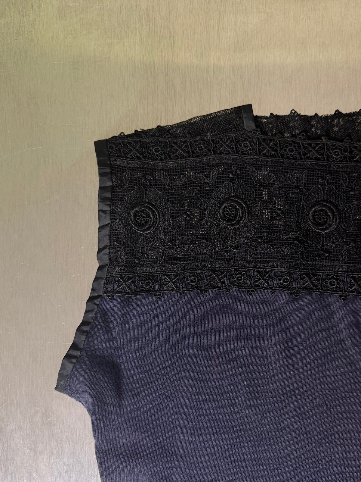 close-up of the black guipure lace yoke detail on the black jersey top, showing the floral medallion pattern