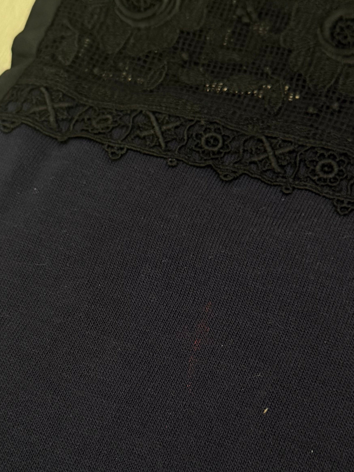 close-up of the black jersey fabric and the scalloped edge of the black lace trim