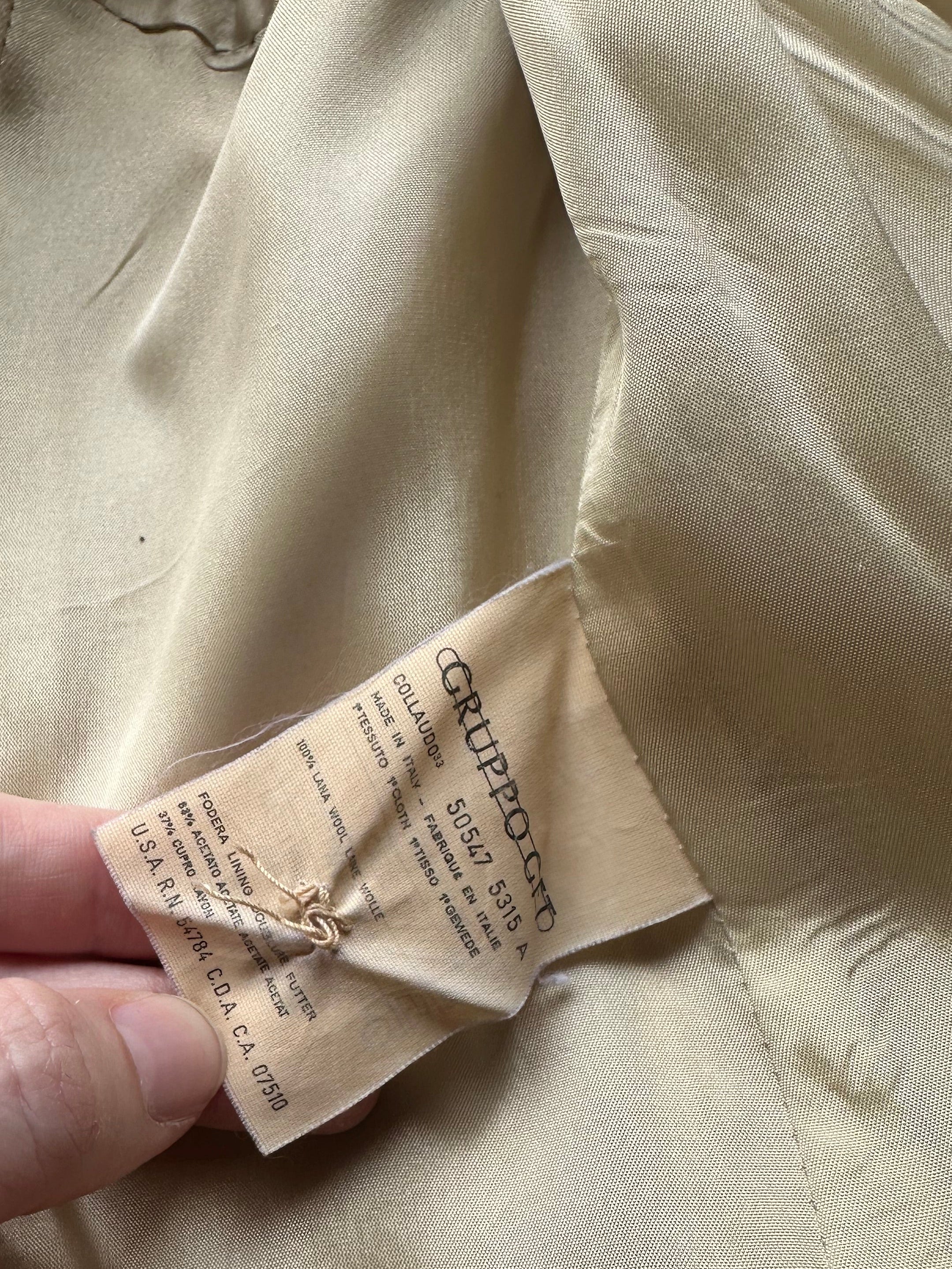 Close-up of a vintage christian dior jacket with a care label held by a hand.