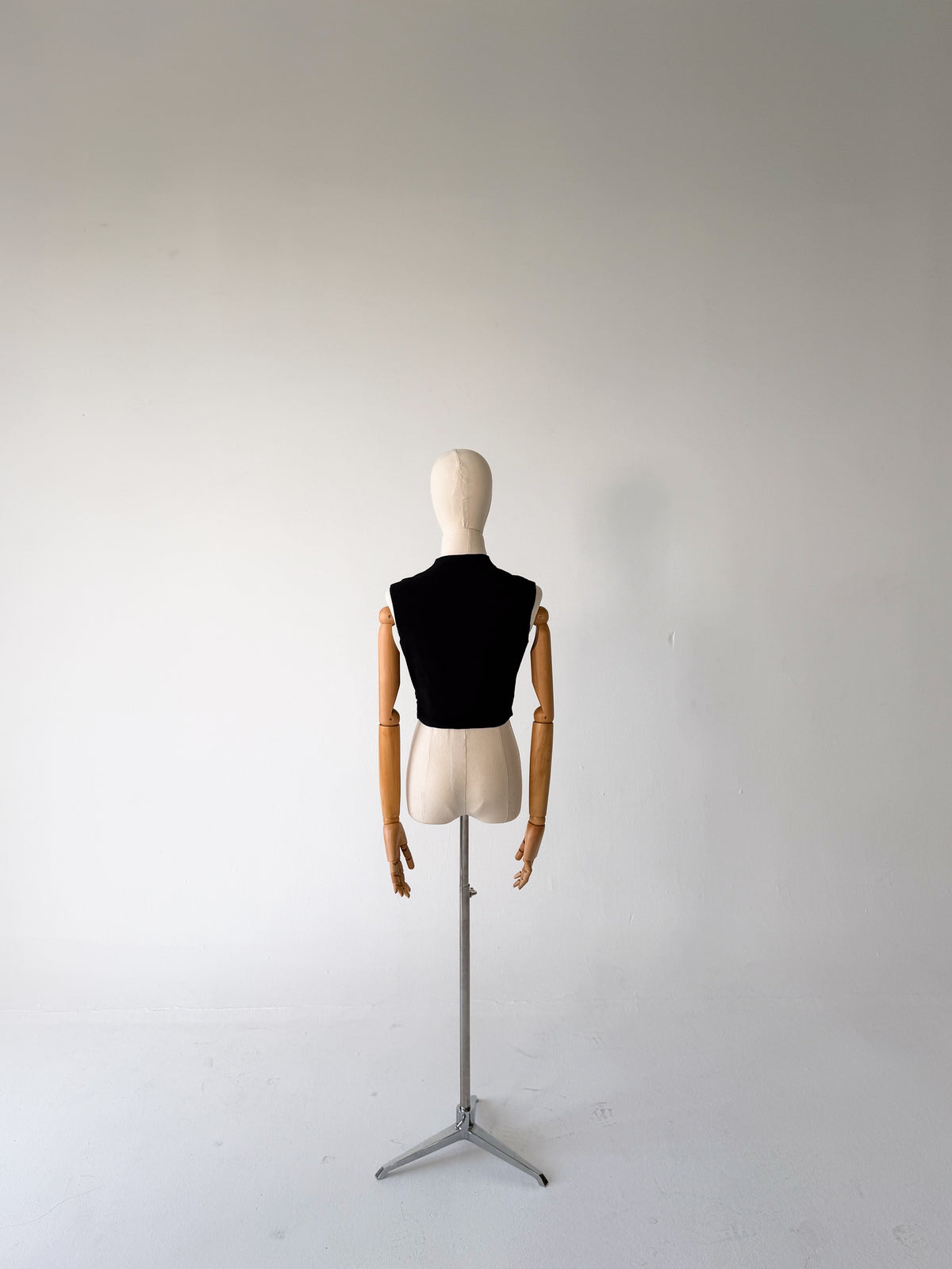 back view of the black scalloped vest on a dress form on a tripod stand