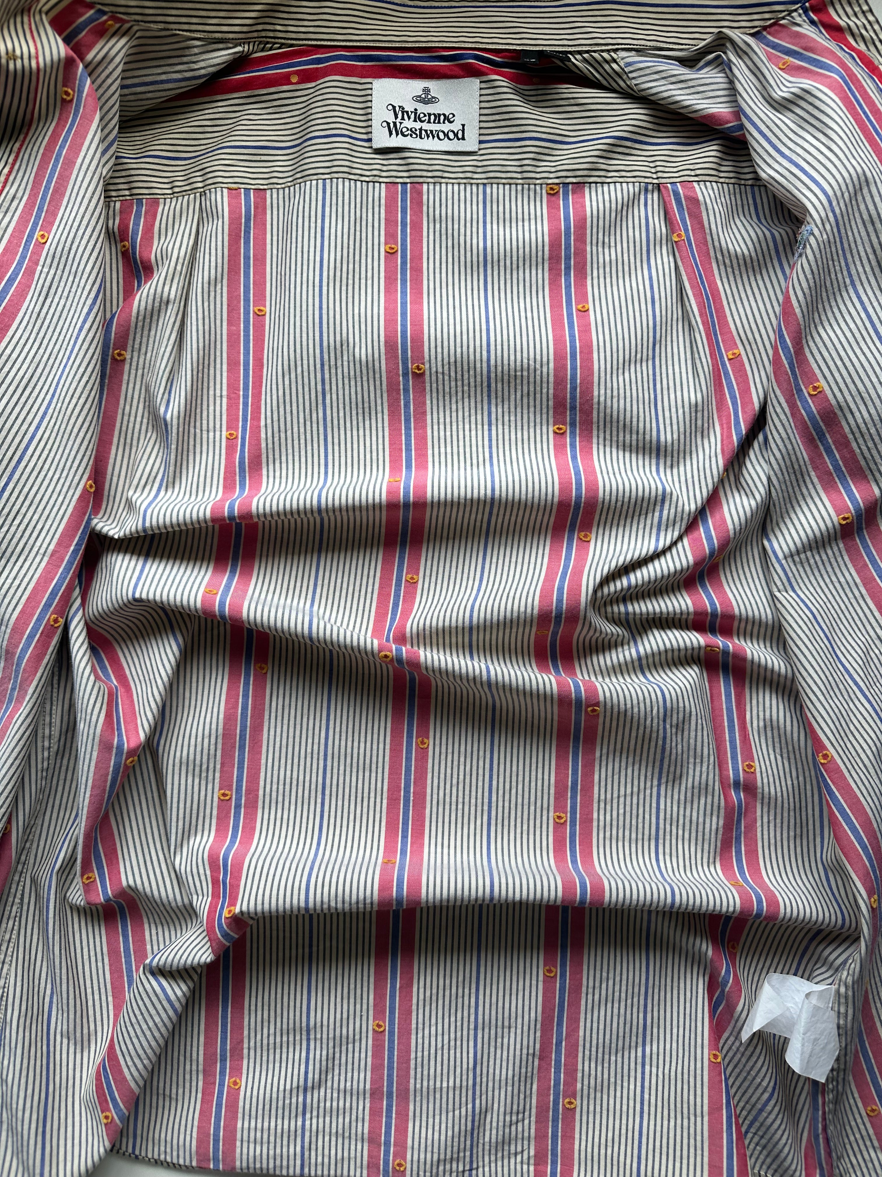 
Interior flat lay of vintage Vivienne Westwood main label shirt showing woven brand label, regimental stripe cotton lining, and orb-printed button detail throughout.