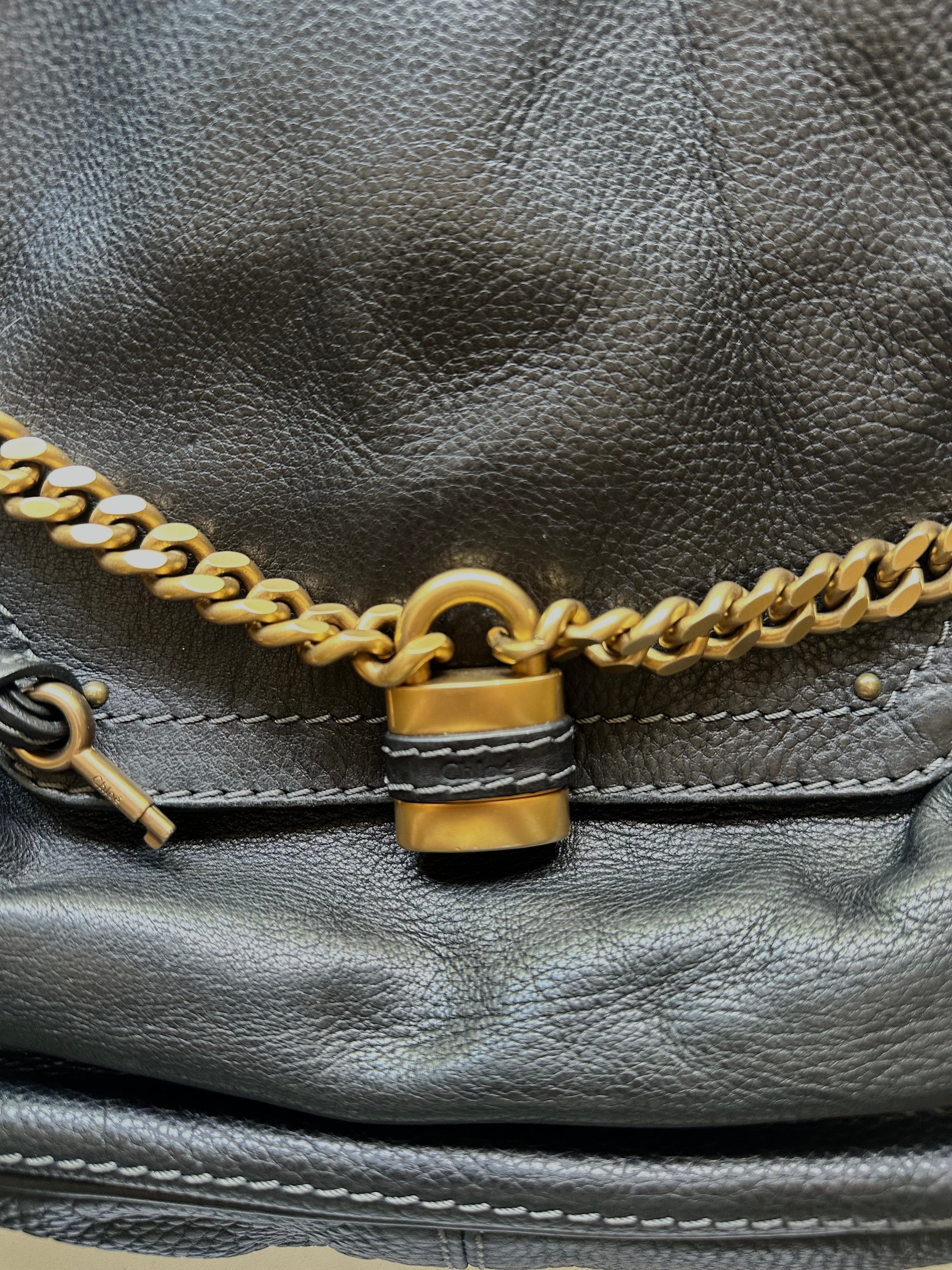 Detail of antique brass padlock and gold chain on vintage Chloé Paddington black leather bag, phoebe philo era