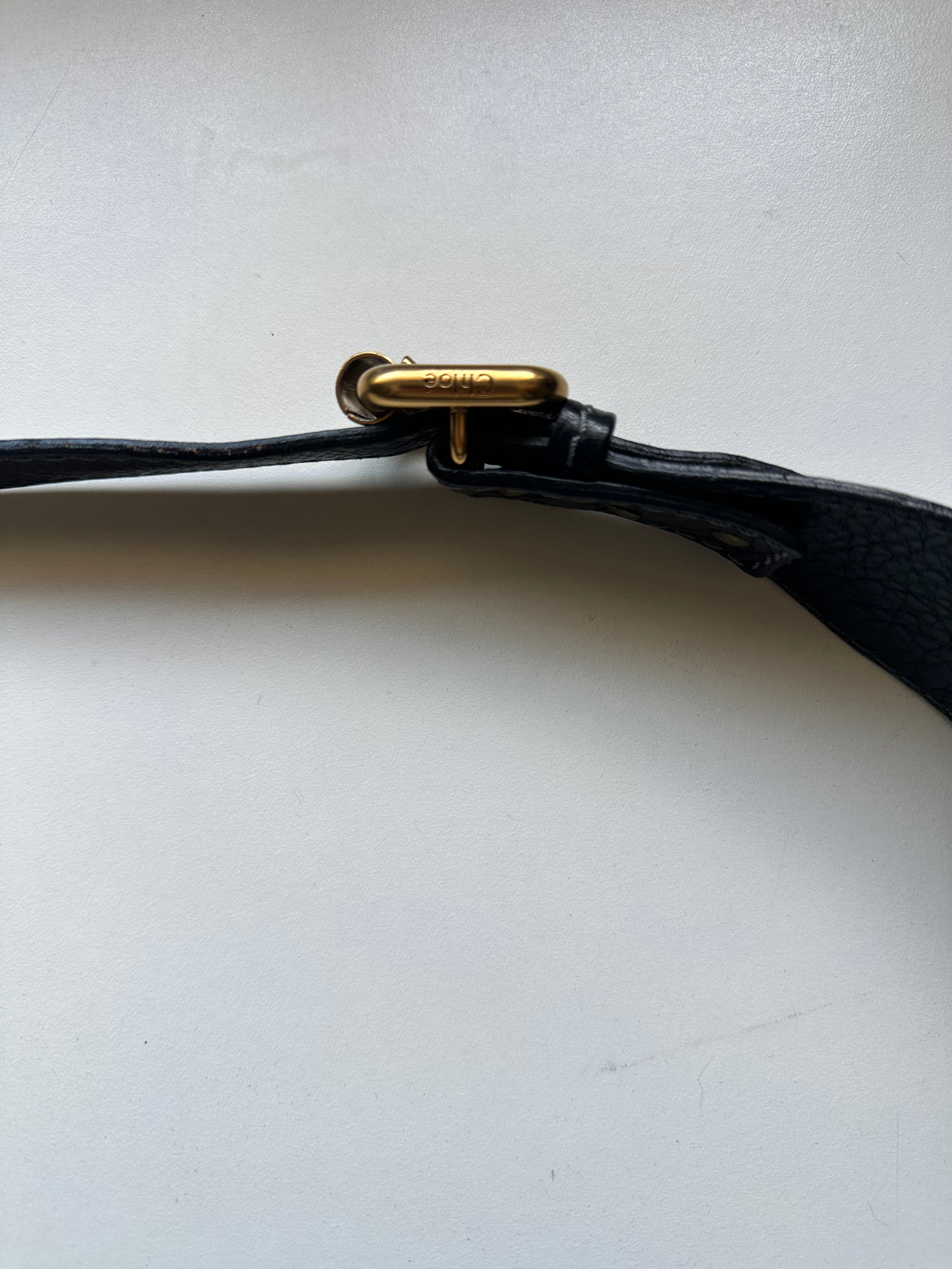 Detail of adjustable leather crossbody strap and buckle hardware on vintage Chloé Paddington bag, black