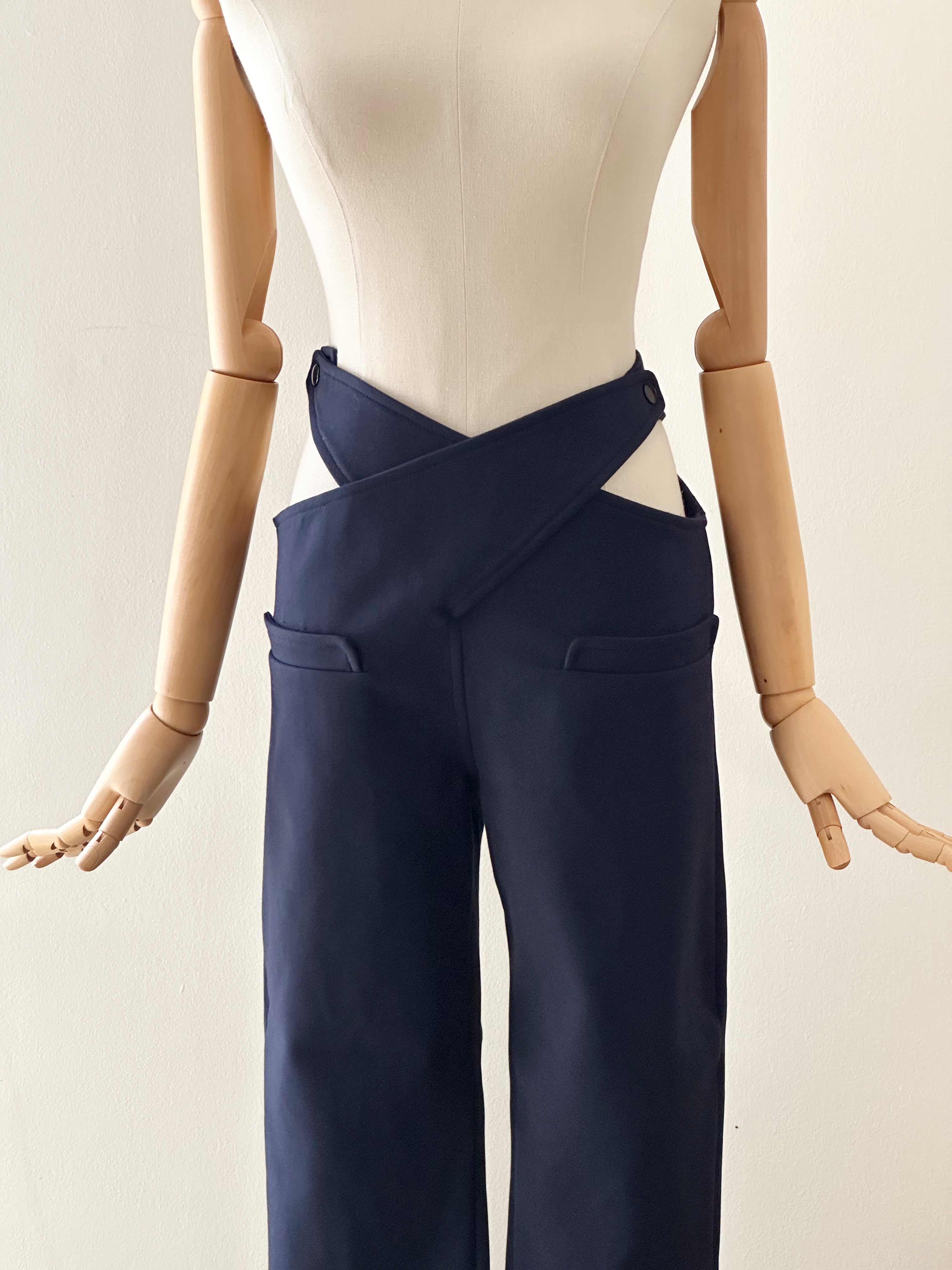 Mannequin wearing a white top and navy pants on a plain background