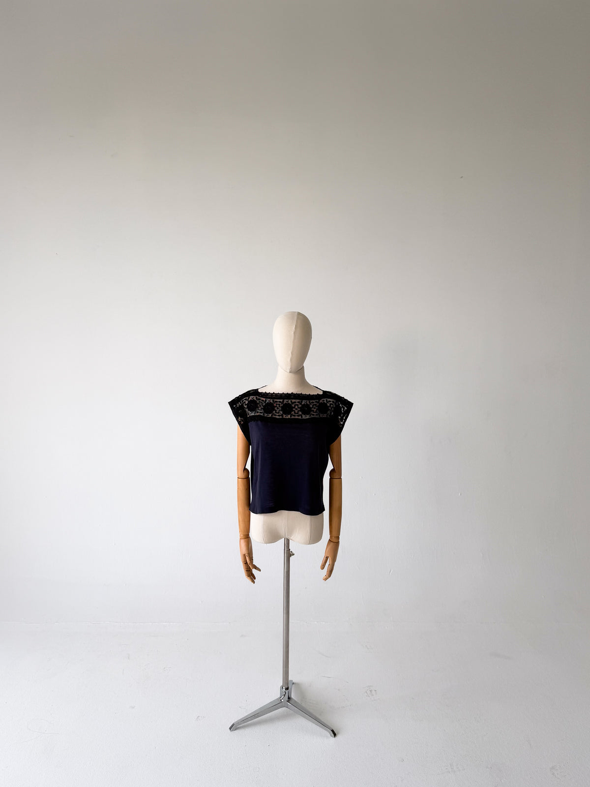 full-length front view of the black jersey top with black lace yoke, styled on a dress form on a tripod stand against a white backdrop